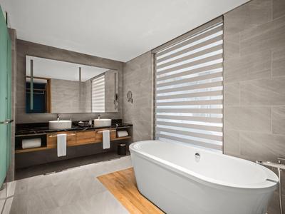 Moderne badkamer met vrijstaand bad, grote spiegelwand en wastafel op houten plank.