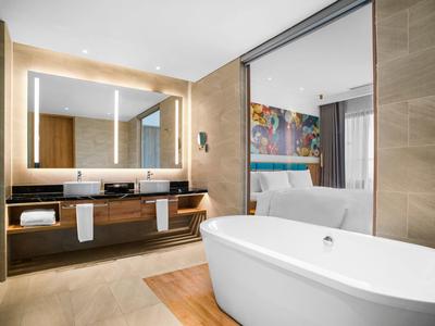 Modern hotelbadkamer met vrijstaand bad en grote spiegel naast de wastafel.