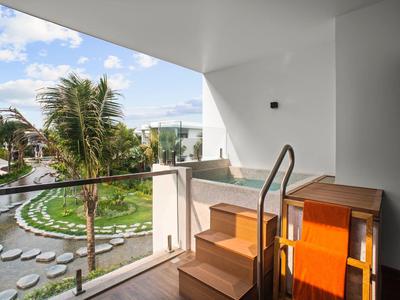 Balkon z widokiem na tropikalny ogród z palmami pod słonecznym niebem.