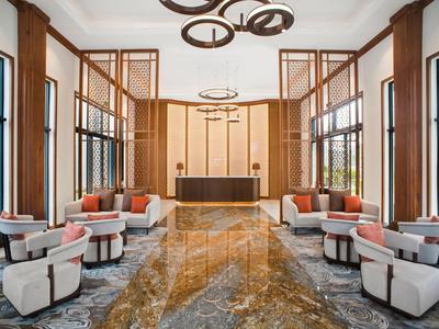 Moderna hall d'hotel con eleganti poltrone, pavimento in marmo e grandi finestre.