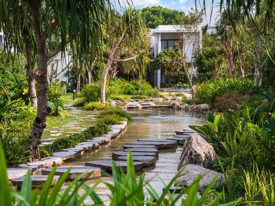 Un sentiero scenico di pietra sull'acqua circondato da rigogliose piante tropicali e alberi.