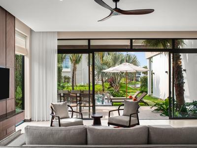 Nowoczesny salon z dużymi szklanymi oknami z widokiem na ogród z miejscami do siedzenia i parasolem.