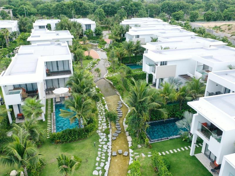 Nowoczesne białe wille z basenami otoczone zielenią i palmami w tropikalnym ośrodku.