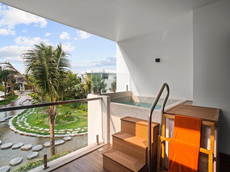 Balkon z widokiem na tropikalny ogród z palmami pod słonecznym niebem.