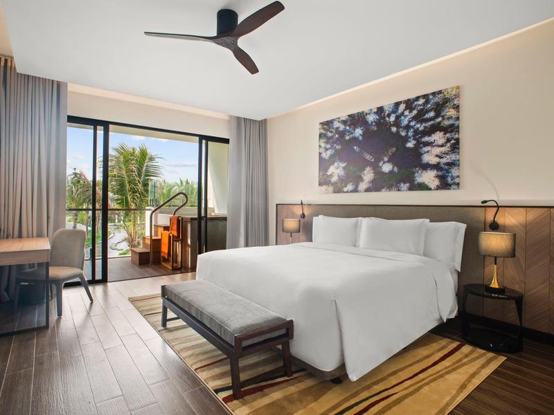 Nowoczesny pokój hotelowy z balkonem, podwójnym łóżkiem i wentylatorem sufitowym.