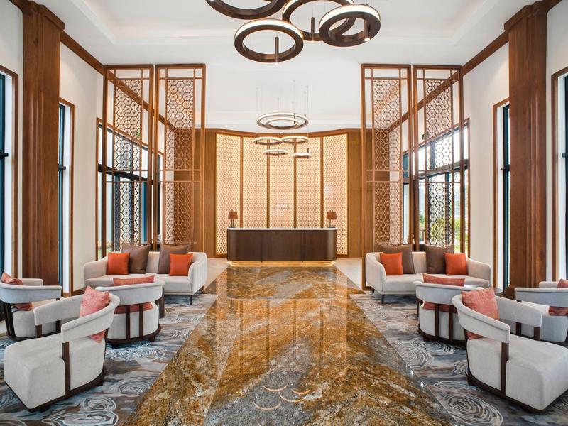 Nowoczesne lobby hotelowe z fotelami, sofami i marmurową podłogą w ciepłych kolorach.