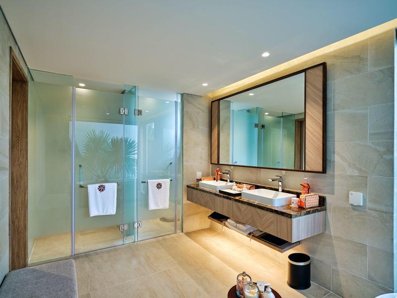 Nowoczesna łazienka z podwójną umywalką, podświetlanym lustrem i szklanymi drzwiami do prysznica.