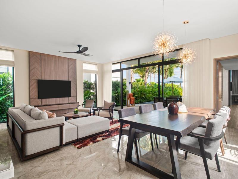 Jasny salon i jadalnia z dużymi oknami, nowoczesnymi meblami i widokiem na ogród.