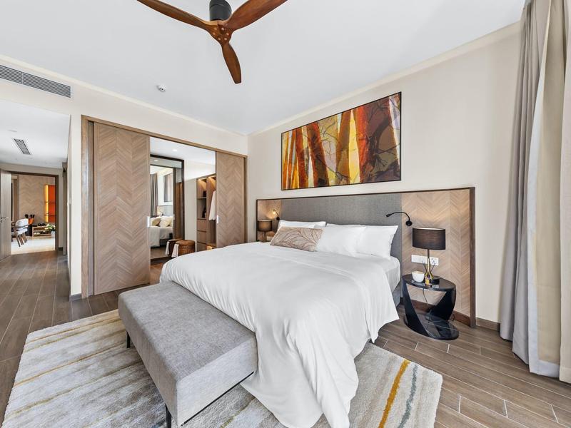 Nowoczesny pokój hotelowy z dużym łóżkiem, dekoracją ściany i wentylatorem sufitowym.