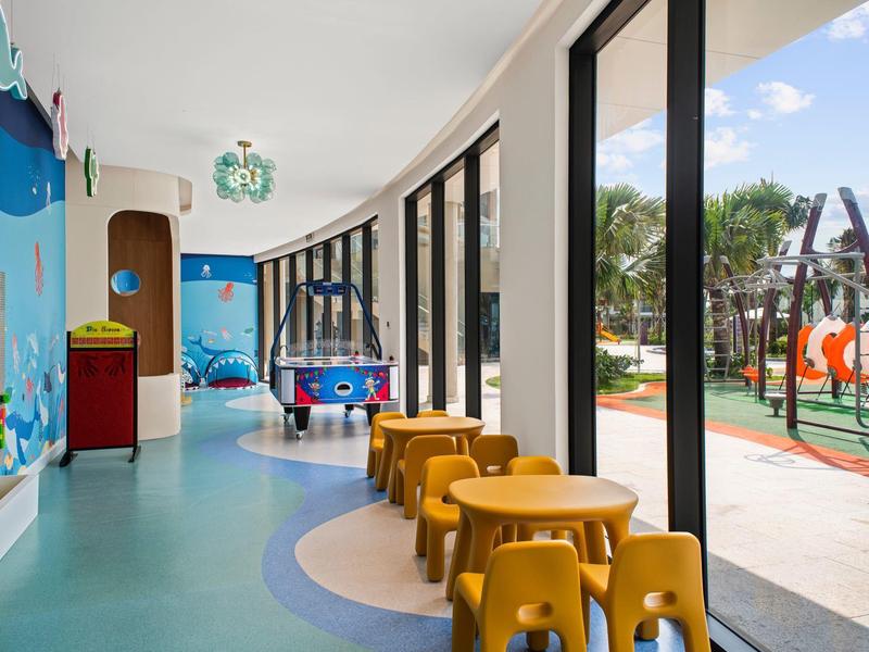 Jasny pokój zabaw dla dzieci z kolorowymi meblami i dużymi oknami na zewnątrz.