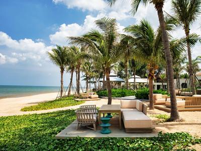 Relaxing beach lounge with palm trees, chairs, and ocean view under sunny weather