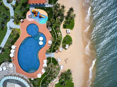 Aerial view of a hotel with a swimming pool, beach, and sea beside it