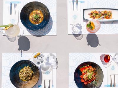 Cuatro platos elegantes y coloridos con bebidas en mesas vestidas de blanco, vista desde arriba.