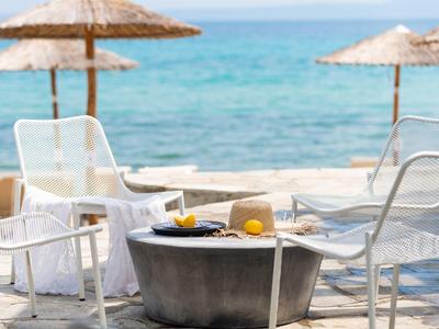 Área de playa con tumbonas blancas y sombrillas frente al mar azul.
