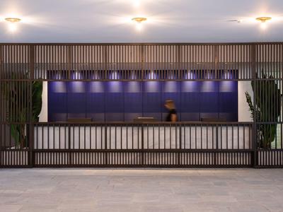 Recepción de hotel moderna con mostrador largo, paneles de madera e iluminación tenue.