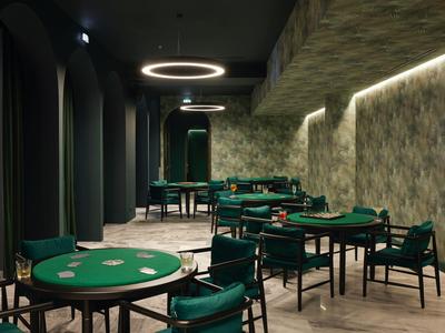 Moderner Spielsaal mit grünen Pokertischen und gedämpfter Beleuchtung.