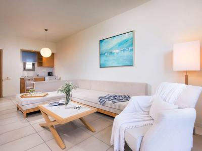 Sala de estar con decoración moderna, sofá, sillón, mesa de centro y iluminación en ambiente claro.