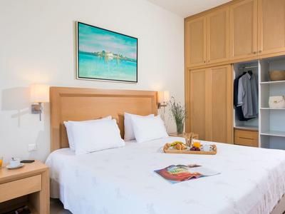 Habitación de hotel moderna con cama grande, mesita de noche y armario abierto.