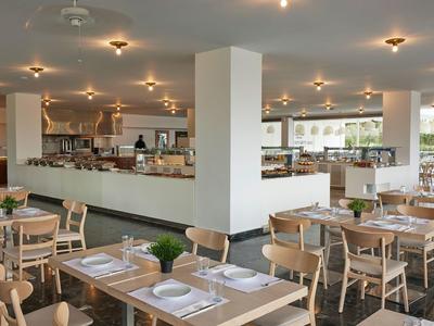 Restaurante moderno con mesas de madera, sillas cómodas y decoración sencilla para huéspedes del hotel.