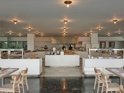 Modern eingerichteter Speisesaal mit Tischen, Stühlen und Buffetbereich in einem Hotel.