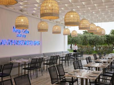 Moderner Außenbereich mit Tischen, Stühlen und hängenden Lampen in Hotelterrasse.