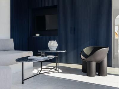 Sala moderna con sofá gris, mesa de centro redonda y pared de acento oscura.