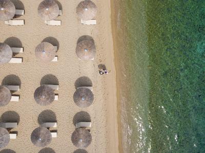 Vue aérienne d'une plage avec parasols, chaises longues et mer turquoise.