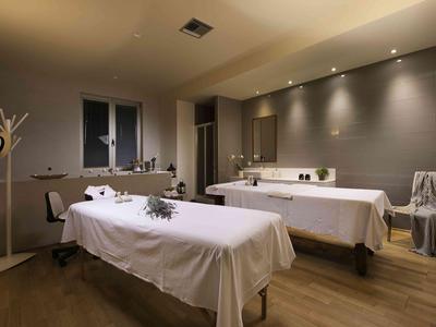 Salle de soins calme avec deux tables de massage, éclairage tamisé et décoration apaisante.