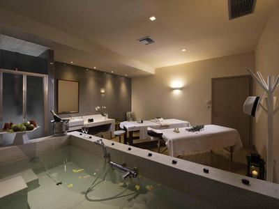 Salle de spa moderne avec deux tables de massage et éclairage doux.