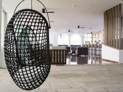 Espace lounge moderne avec fauteuils suspendus noirs et intérieur blanc dans un hôtel.