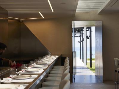 Espace de restaurant d'hôtel moderne avec tables élégamment dressées et vue extérieure.