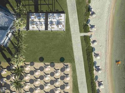 Vue drone d'une station balnéaire avec parasols, transats et accès à la plage.