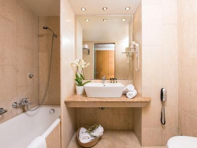Salle de bains moderne avec baignoire, lavabo, miroir et éclairage simple dans un hôtel.