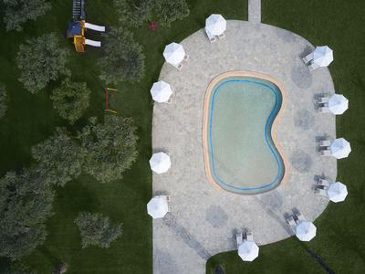 Vue d'ensemble d'une petite piscine entourée de parasols blancs et d'une pelouse verte.