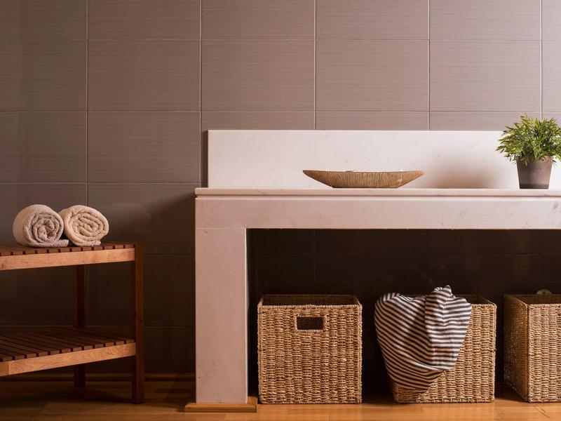 Área moderna con estantes blancos, cajas de mimbre y toallas dobladas en un estante de madera.