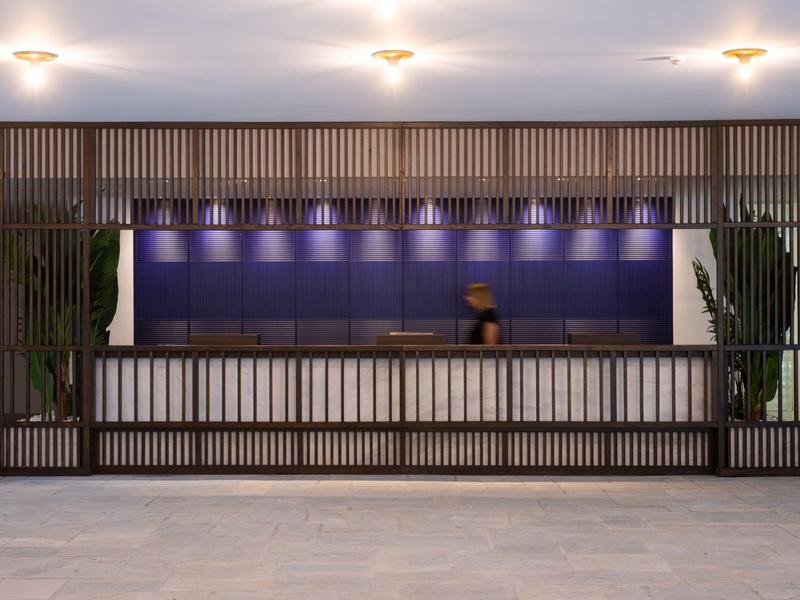 Recepción de hotel moderna con mostrador largo, paneles de madera e iluminación tenue.