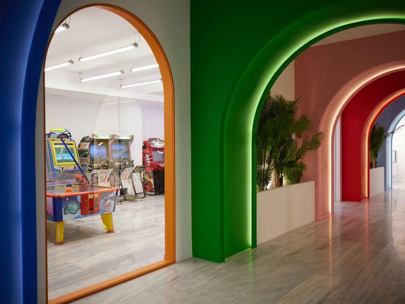 Pasillo con arcos coloridos que conducen a una sala de juegos con máquinas arcade en un hotel.