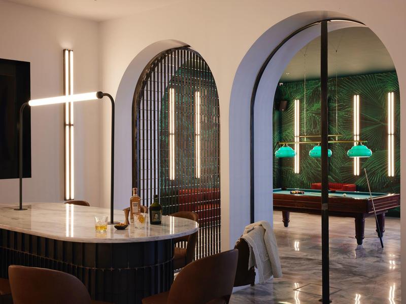 Área elegante de hotel con mesa moderna, sillas y espejo iluminado con luz suave.
