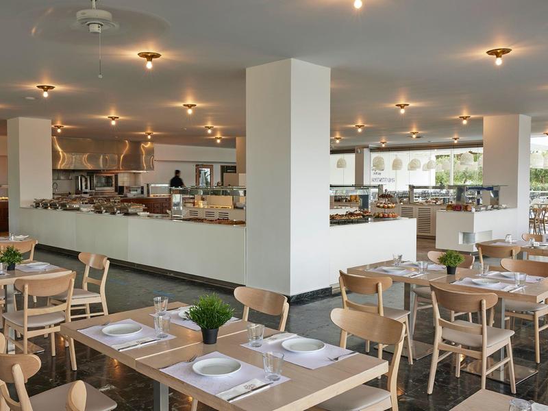 Restaurante moderno con mesas de madera, sillas cómodas y decoración sencilla para huéspedes del hotel.