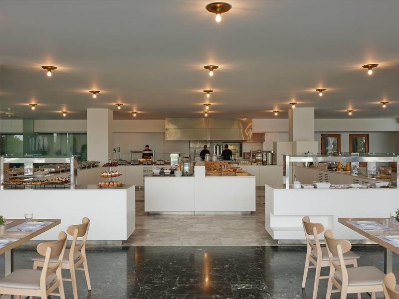 Comedor moderno de hotel con interior claro y plantas decorativas en las mesas.