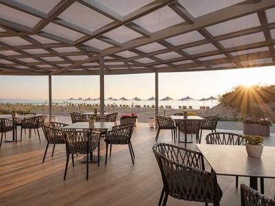 Terrasse mit Stühlen und Tischen mit Blick auf das Meer und den Sonnenuntergang.