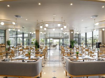 Helles, modernes Restaurant mit grauen Sitzbänken und Dekoration in Holz und Grün.