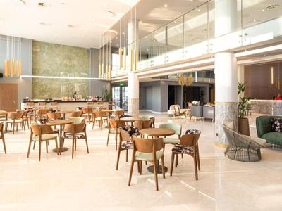 Amplio comedor luminoso con sillas y mesas de madera en un interior moderno de hotel.