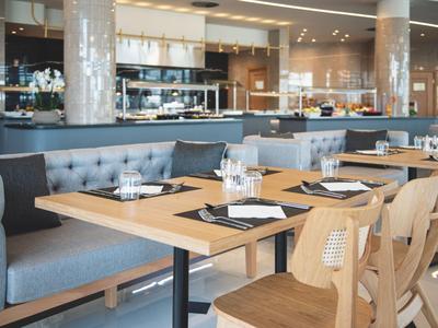 Modernes Restaurant mit Holztischen, bequemen Sitzbänken und Stühlen, eleganter Beleuchtung