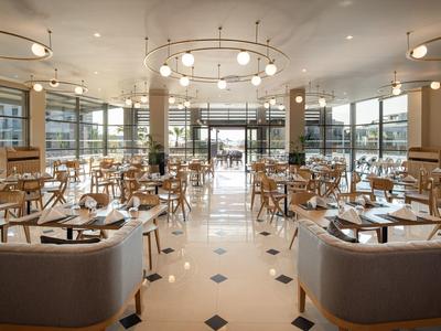 Espacioso restaurante moderno con muebles de madera y grandes ventanales.