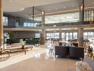 Gran área abierta del vestíbulo del hotel con mobiliario moderno y luz natural.