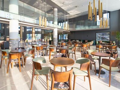 Helles, modernes Restaurant mit Holzstühlen und großen Fenstern in einem Hotel.