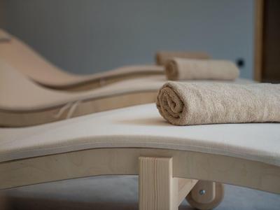 Tres tumbonas blancas con toallas enrolladas en un área interior tranquila.