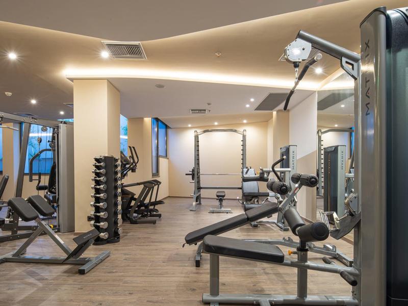 Sala de fitness moderna con varios equipos de entrenamiento y pesas en un espacio iluminado.