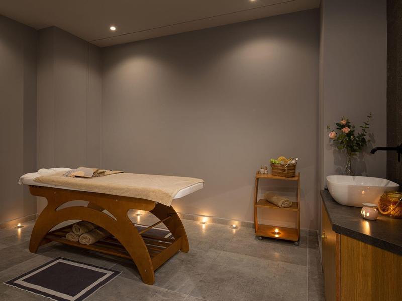 Sala de masajes con iluminación cálida, mesa de madera y ambiente relajante en un spa.